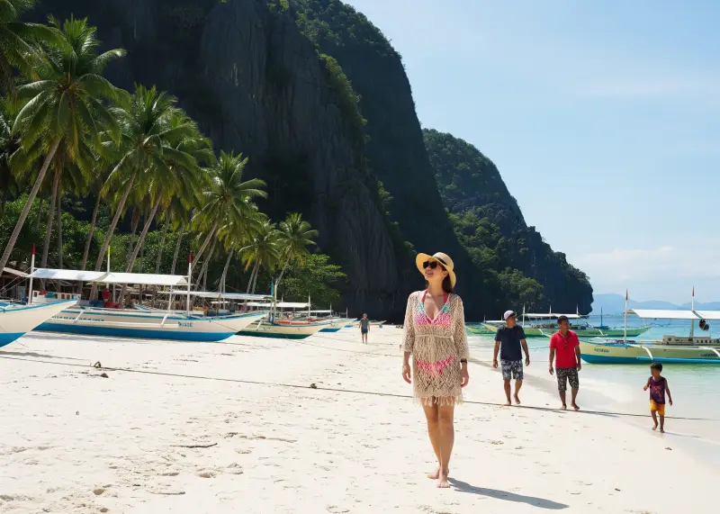 gigantes islands filipina beach scene Filipina in bikini and net dress enjoying the beach at Gigantes Islands with cliffs and boats in the background.