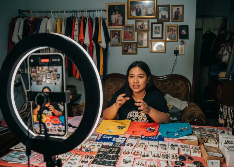tiktok live online selling philippines Filipino TikTok live seller showcasing products in a modest sala.