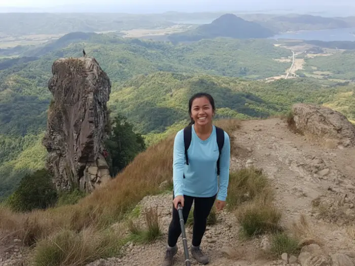 filipina hiker pico de loro selfie taking a selfie with her phone on a trail overlooking the majestic landscape of Mount Pico de Loro