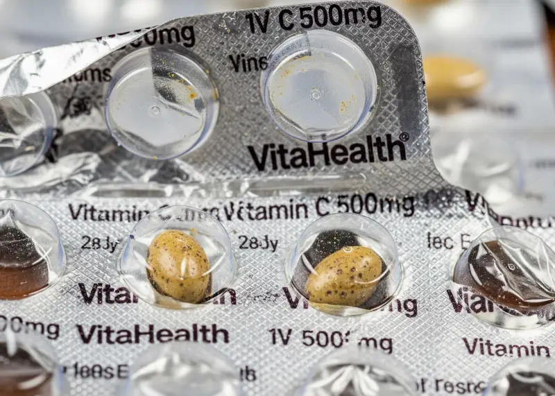 red flags fake vitamins Close-up of suspicious vitamin blister pack with uneven tablets and misprinted foil.