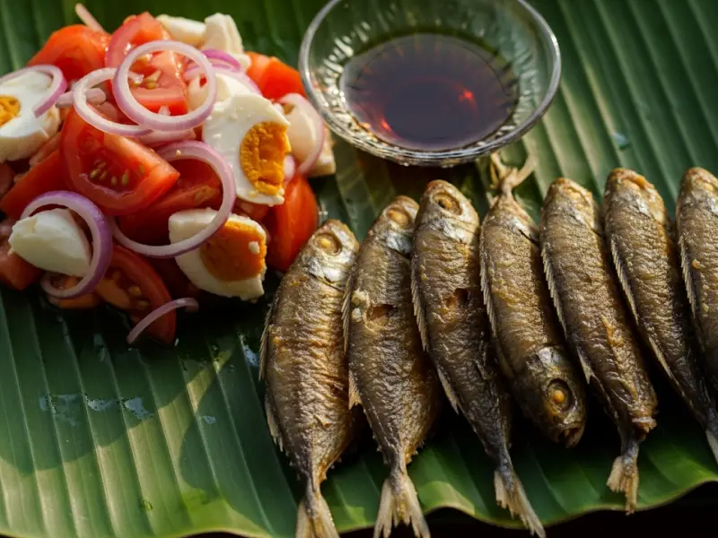 pritong galunggong ensalada itlog maalat Fried galunggong served with tomato and salted egg ensalada on a banana leaf plate.