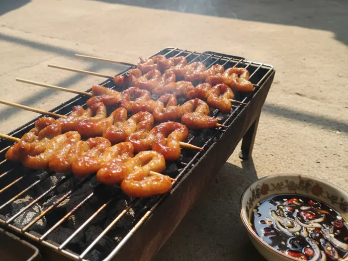 isaw filipino grilled chicken intestines Grilled isaw skewers Filipino street food with spiced vinegar dip