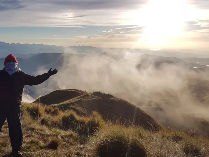 mount pulag summit sea of clouds sunrise view Filipino hiker raising arms at Mount Pulag summit above the rolling sea of clouds.