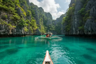 Small Filipino boat gliding through turquoise waters of Sohoton Cove in Bucas Grande, Surigao del Norte.
