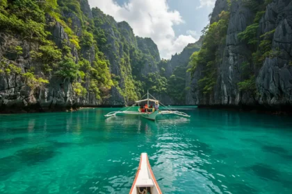 Small Filipino boat gliding through turquoise waters of Sohoton Cove in Bucas Grande, Surigao del Norte.